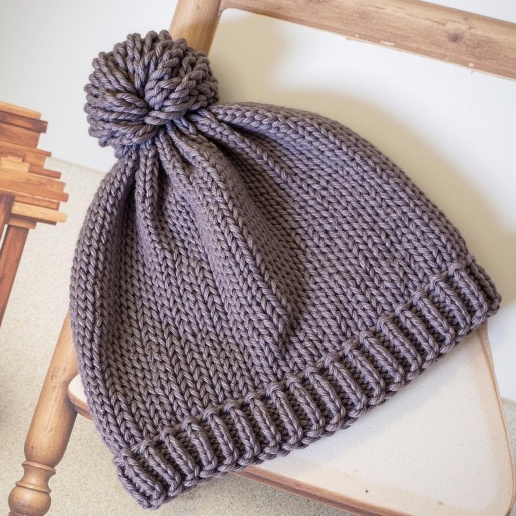 A completed knitted ponytail hat displayed on a wooden table