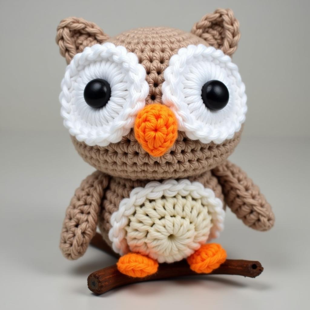 Free Amigurumi Owl Pattern: A crocheted owl with large eyes perched on a branch.