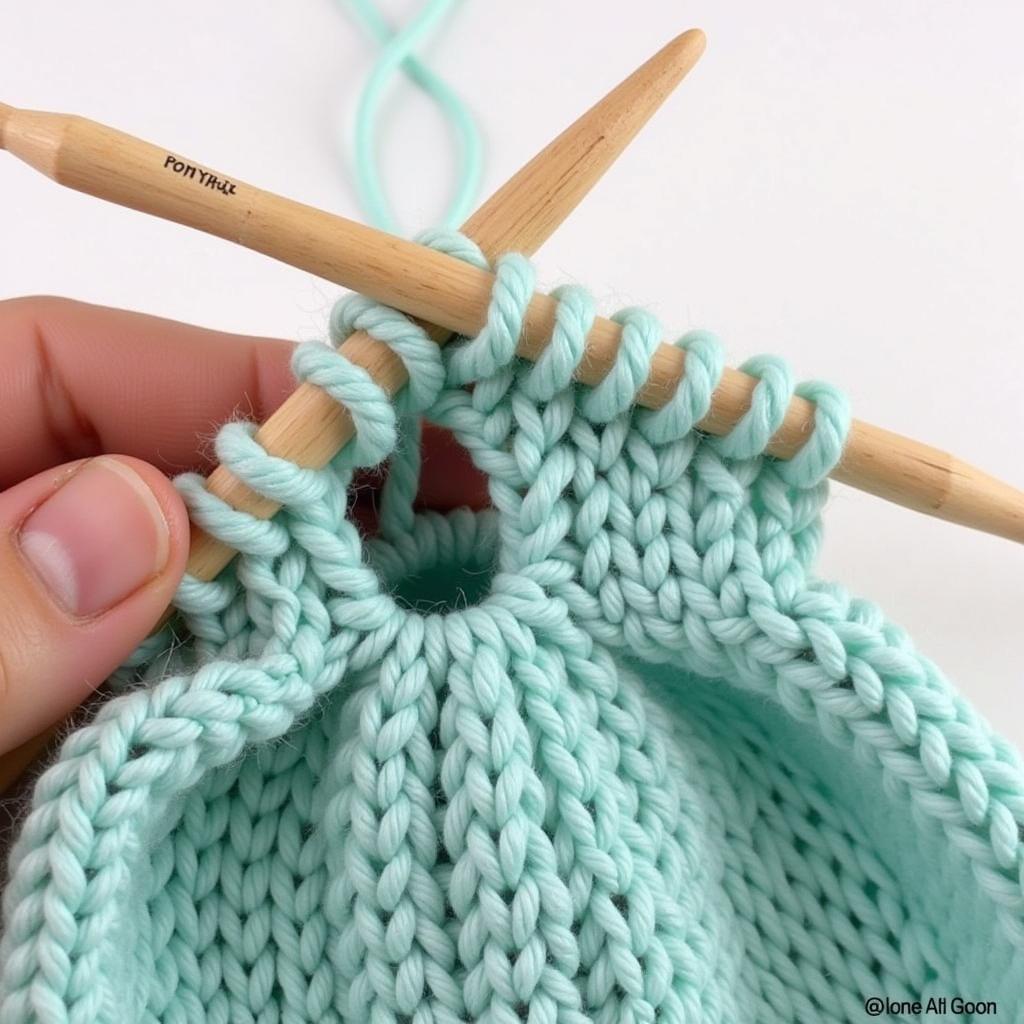 A close-up shot of knitting needles creating a ponytail hat