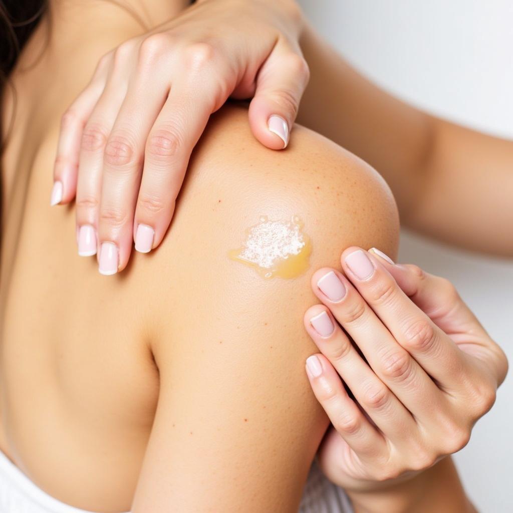 Close-up of a person applying castor oil to their skin.